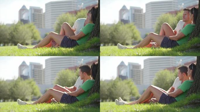 恋爱中的情侣坐在城市公园的树下