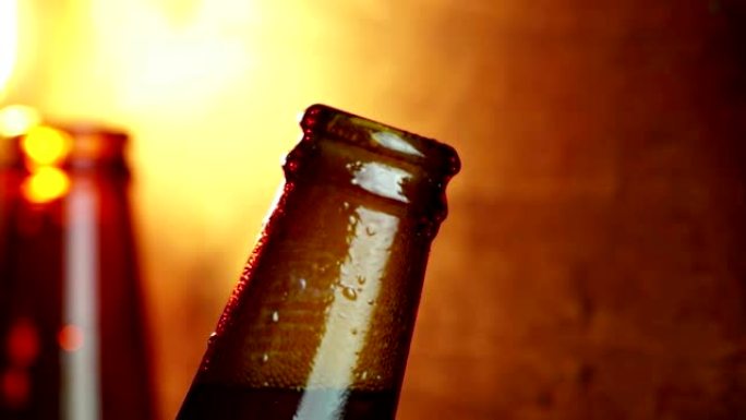 男子在温暖的灯光下打开一瓶带有泡沫的新鲜啤酒