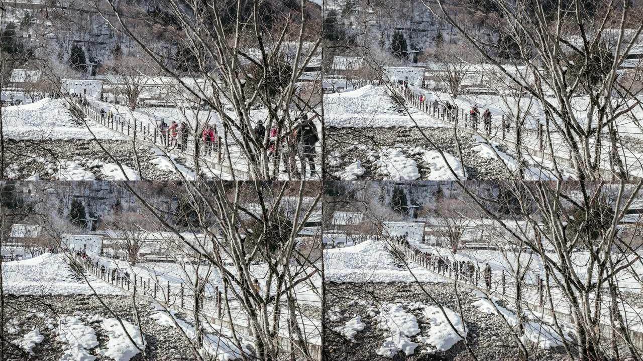 白雪白雪的Shirakawago村和游客在日本使用悬挂木桥穿越山谷的人群
