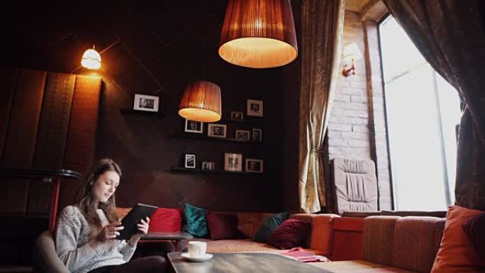 年轻女子在咖啡店喝咖啡并使用平板电脑