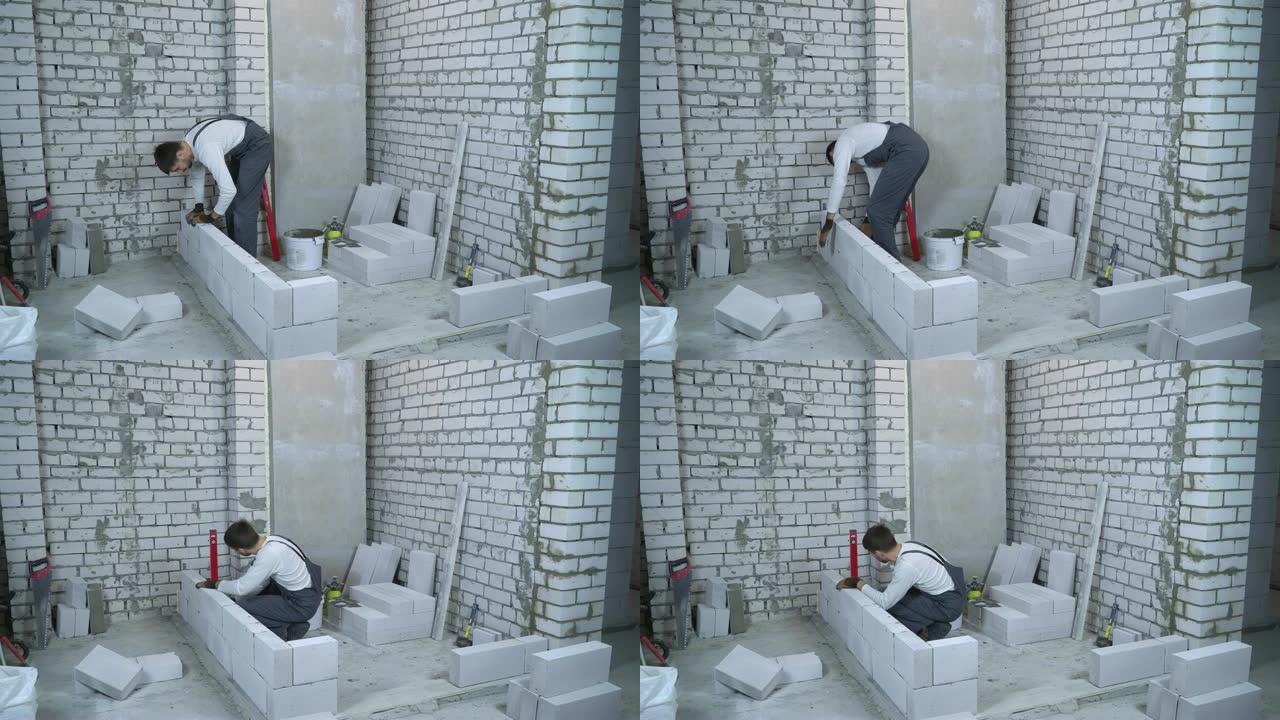 男性建筑商铺设加气混凝土砌块并检查气泡水平