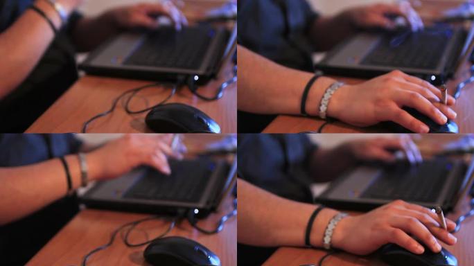 男子在使用笔记本电脑时拿着香烟的细节