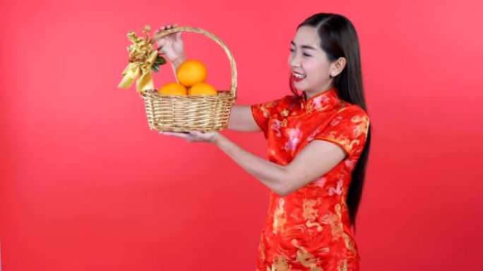 穿着旗袍的女人在篮子里拿着橘子