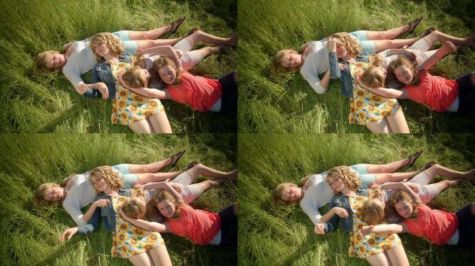 一组4个女孩躺在田野里，她们互相挠痒痒，玩草