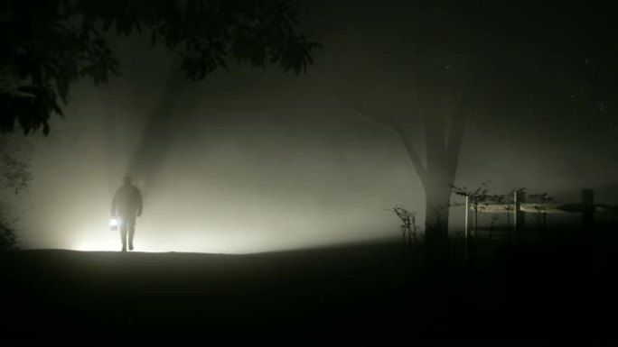 男人在漆黑的夜晚从雾中走出来