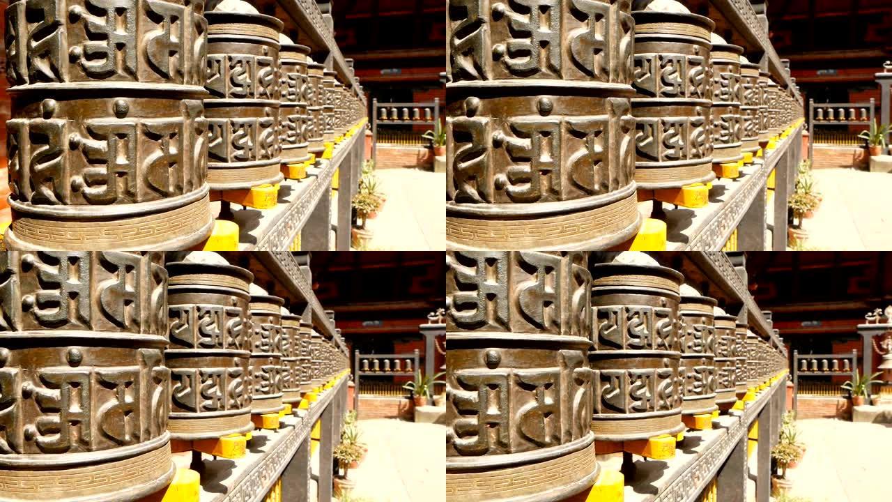 尼泊尔加德满都杜巴广场的寺庙院子里，一排古老的祈祷轮或鼓，上面有咒语“唵摩尼?帕德美”。西藏佛教。