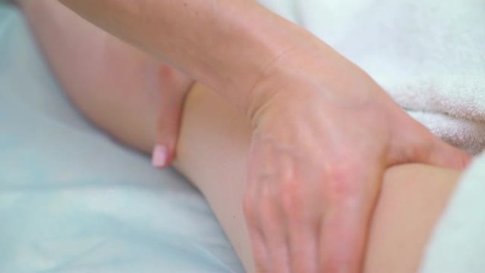 女性按摩师手在女性大腿上做消脂按摩的特写