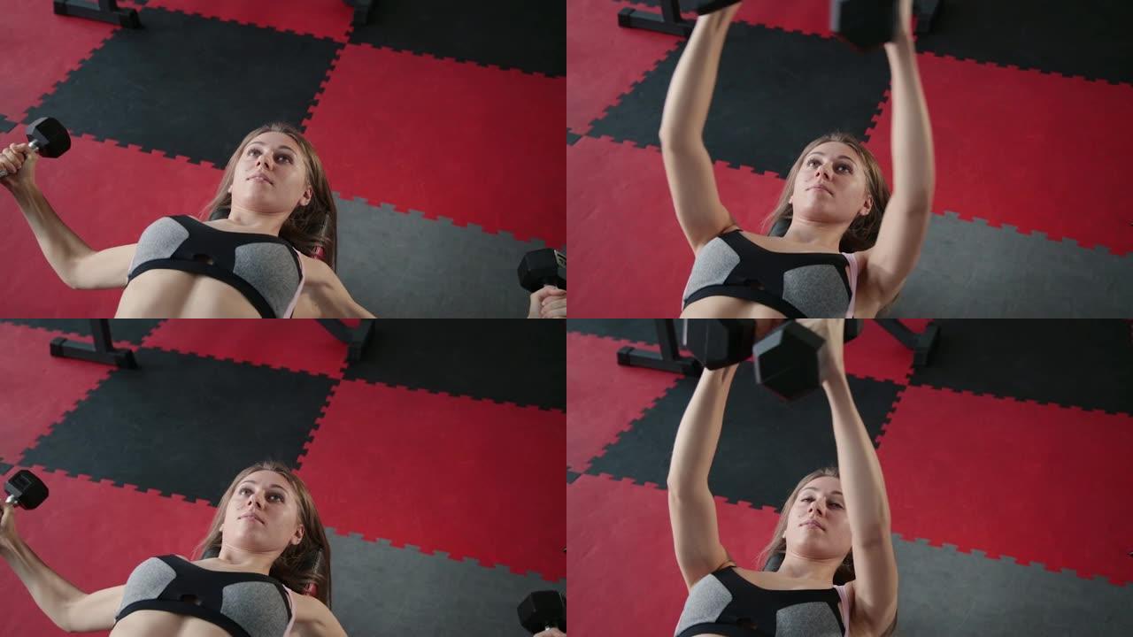 美丽的运动少女哑铃在健身房锻炼胸肌