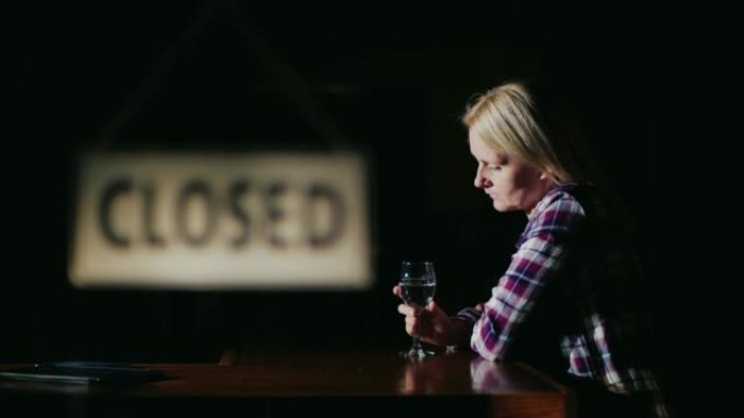 一个中年妇女在已经关闭的商店或酒吧的窗户外独自喝酒。工作压力