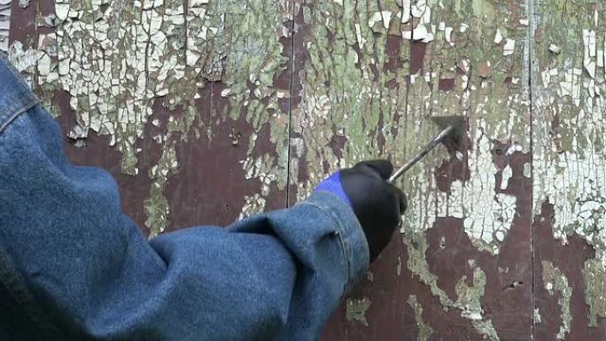 工人从木门上报废旧的破裂油漆