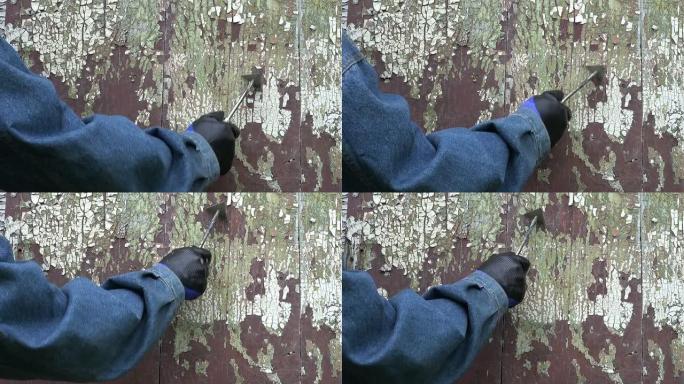 工人从木门上报废旧的破裂油漆