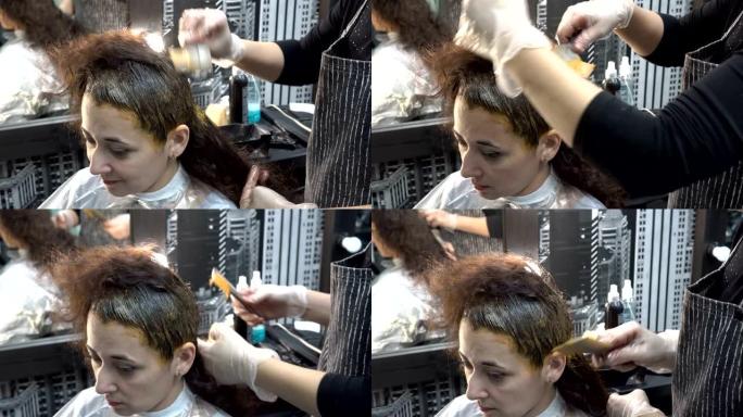 特写镜头，这位美发师-造型师在理发店画了一个亚洲女孩的头发，并用刷子在她的头上涂了油漆。头发护理。4