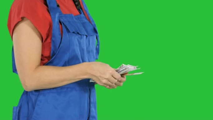 一个穿着工人衣服的女人在绿屏上数钱，色键