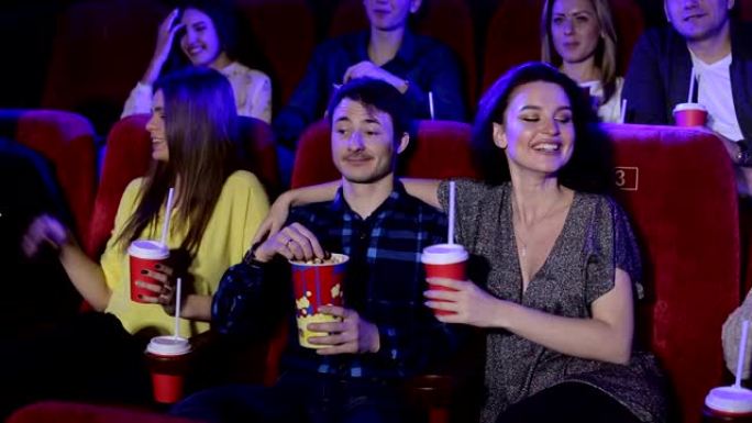 一群在电影院看电影的朋友。朋友们在电影院扔爆米花。