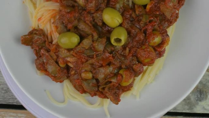乡村木桌上的意大利面条。地中海美食搭配意大利面 -- 肉酱、橄榄油、罗勒和番茄。旋转射击。4k分辨率