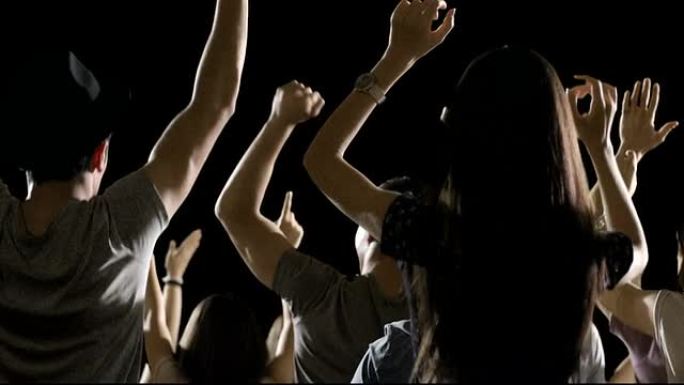 一群粉丝在黑色背景上跳舞。音乐会，跳跃，跳舞。慢动作。在红色史诗电影相机上拍摄。