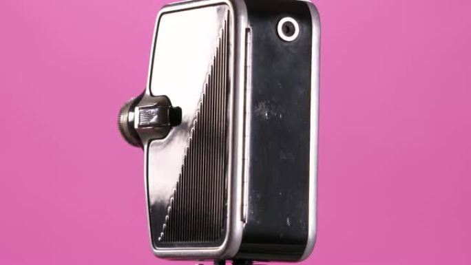 粉红色背景上的微型复古8毫米电影相机