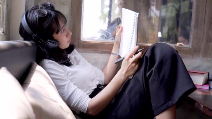亚洲一名女子在咖啡馆里工作，用笔记本电脑听音乐