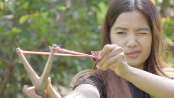 年轻的亚洲女子用弹弓瞄准