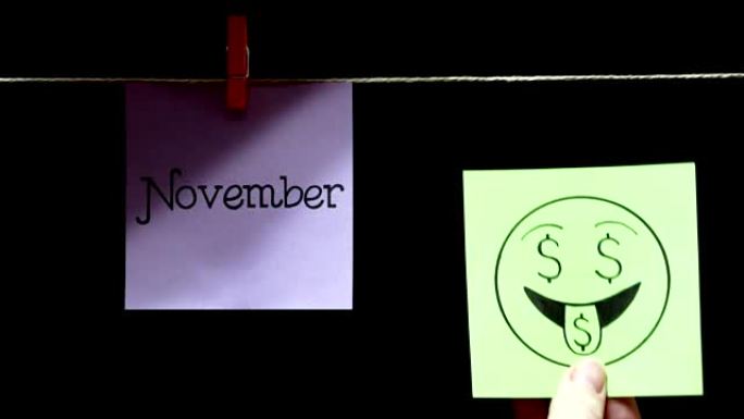 两个贴纸。情感。在丁香的左边，有一张写着十一月的纸。在右边的绿色单子上，脸上表达着爱钱的表情。黑色背