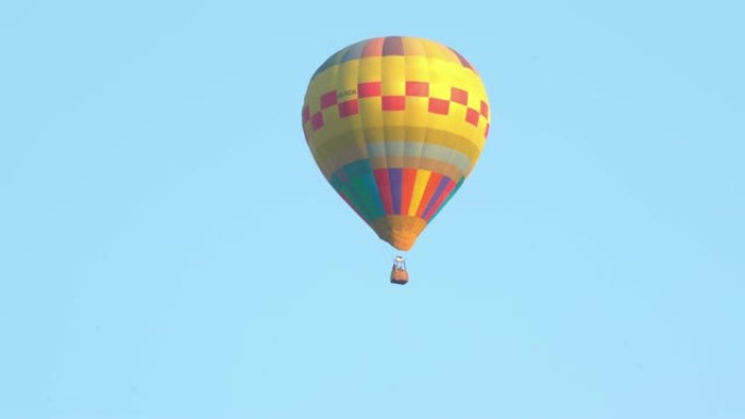 在壮观的白色天空和绿色屏幕或色度键背景下，从左向右飞行的黄色彩色单个热气球的4k视频跟踪镜头。