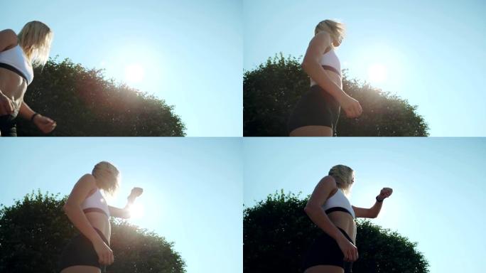 低健康角度的金发女子完成跑步训练，站在阳光下，检查她的智能手表进行心率监测