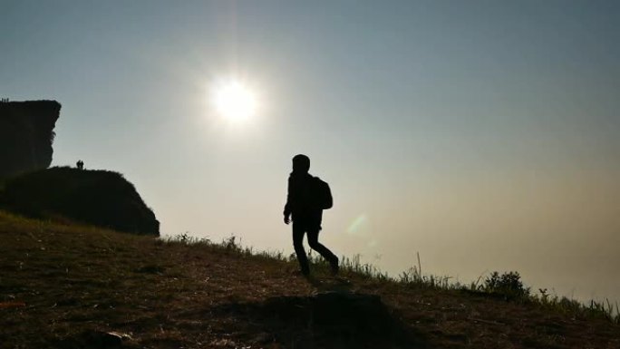 日落或阳光下在山上行走的人的剪影。