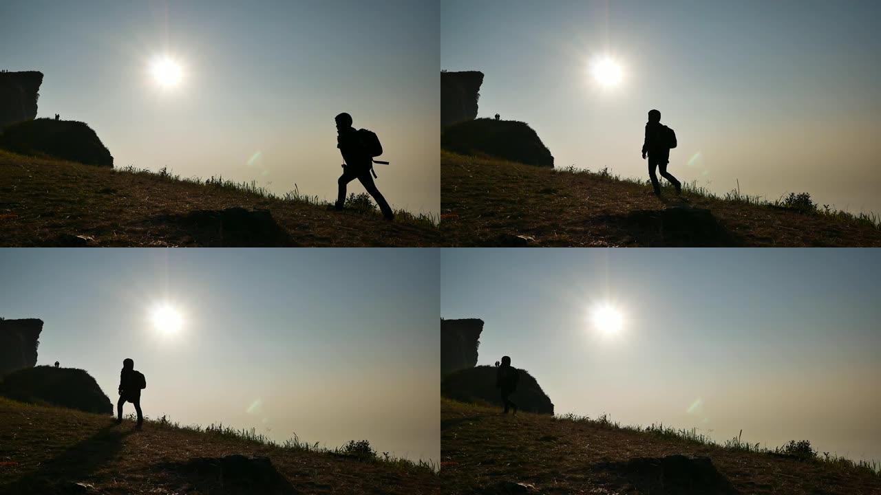 日落或阳光下在山上行走的人的剪影。