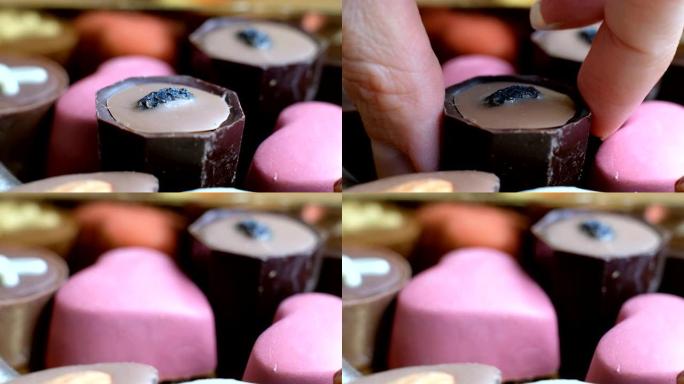 女人从盒装美味甜点背景中选择什锦巧克力。特写，宏