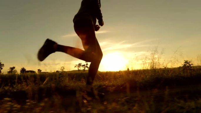 日落时跑步慢动作的女人的剪影，概念锻炼和健康，慢动作