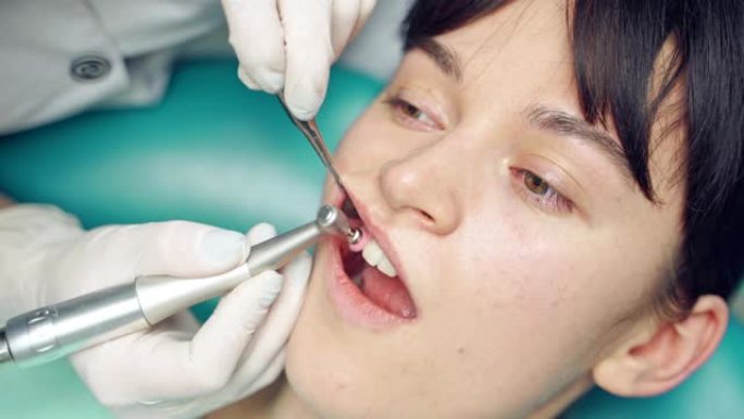 牙医正在牙科中心为客户清除牙齿上的沉积物并美白。
