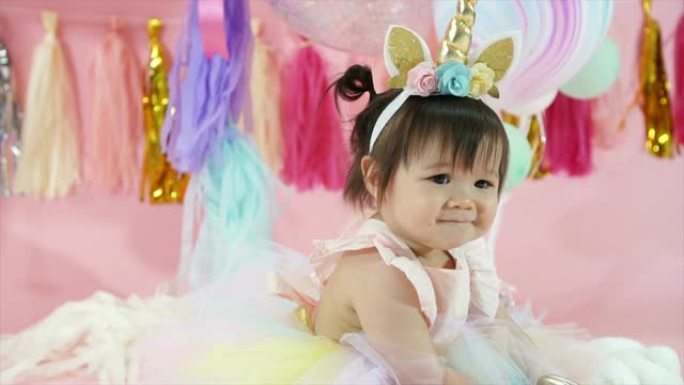 可爱的高加索蹒跚学步的女婴在生日派对上，微笑着拍手。带有精美装饰的快乐庆祝时刻