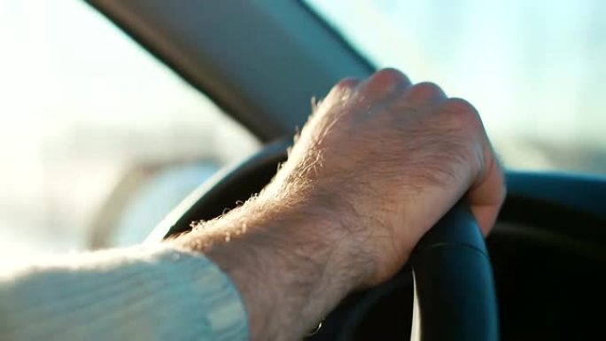 一名男子在高速公路上开车。紧闭方向盘上的手