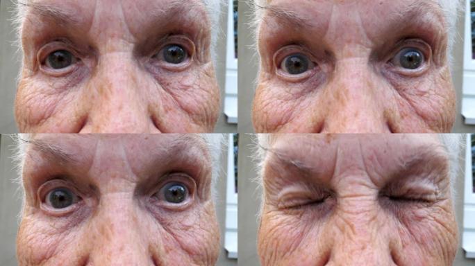 用惊讶的表情将老祖母皱着皱纹的脸对着镜头。成熟女人的肖像强烈地扭曲了她灰色的眼睛。慢动作