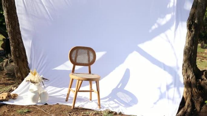 空木椅后面被风吹起的白色窗帘。