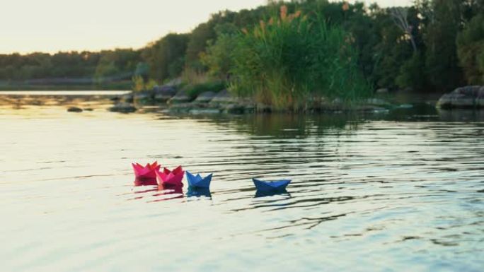 不同的彩色纸船在自然背景上绿树成荫的快速河面中游泳。