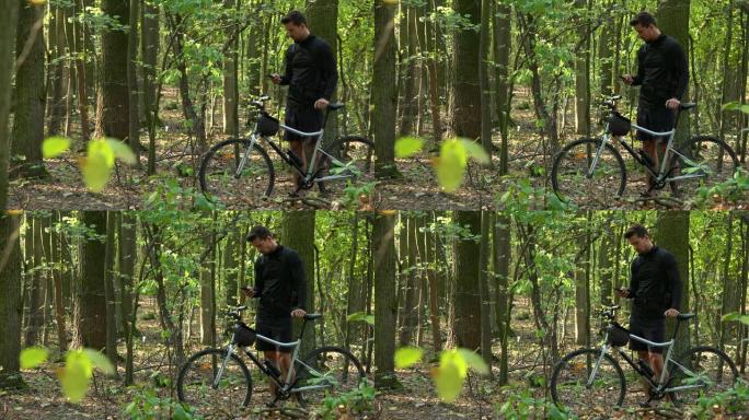 骑自行车的人站在森林里骑自行车，用智能手机工作