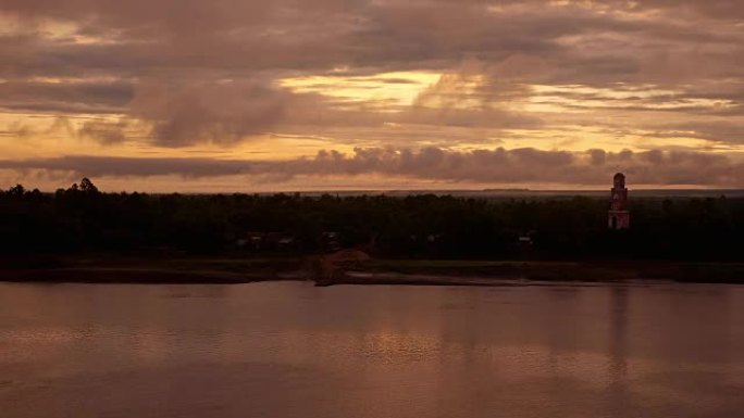 河上的日出和背景中河边望塔上的多云天空