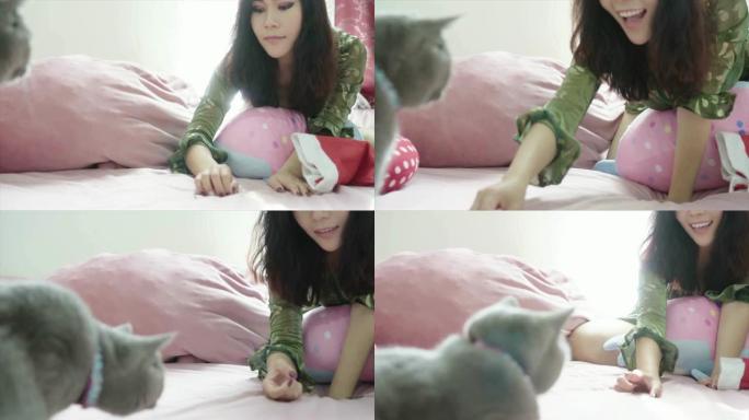 美丽的亚洲女人在家里的床上玩可爱的猫品种