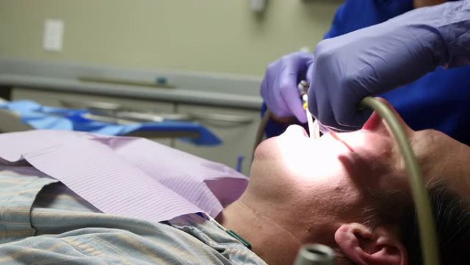 牙医抓住牙科设备真空并清洁口腔