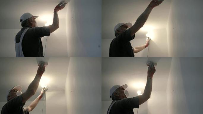 工人完成工作，站在梯子上时用砂纸打磨天花板，另一只手用灯泡