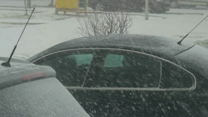 镇上的暴风雪。城市里积雪覆盖的汽车。清晨，城市降雪，从窗户可以看到。雪堆。雪树，汽车。
