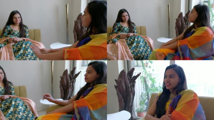 两个穿着民族服装的印度女孩朋友快乐而开朗，他们互相分享和交谈，微笑着，稳定的手持镜头