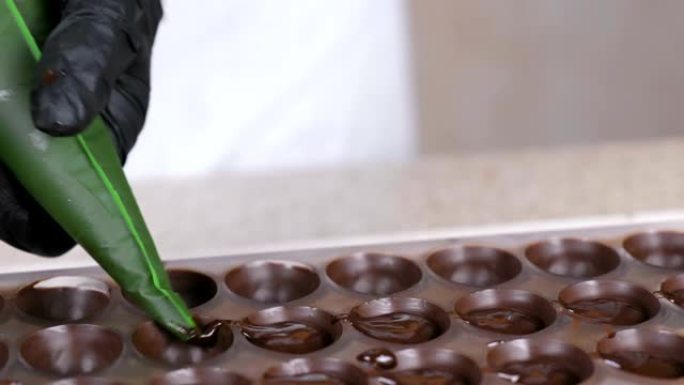 贝克的手从糕点袋中倒出液态巧克力填充果仁糖。