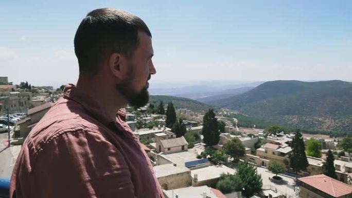 年轻人看着山，享受风景自然背景。以色列上加利利的萨法德。度假概念。