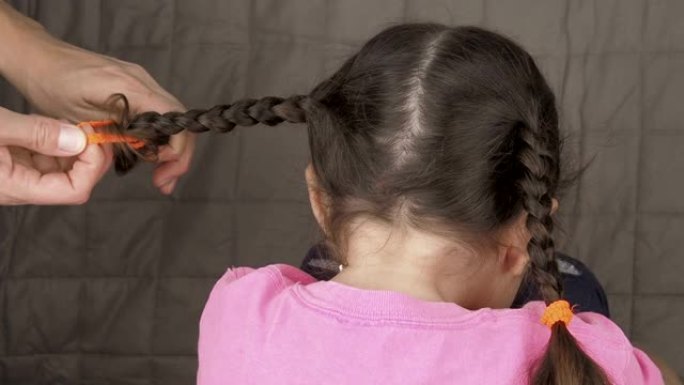 一个女人给一个女孩编辫子。