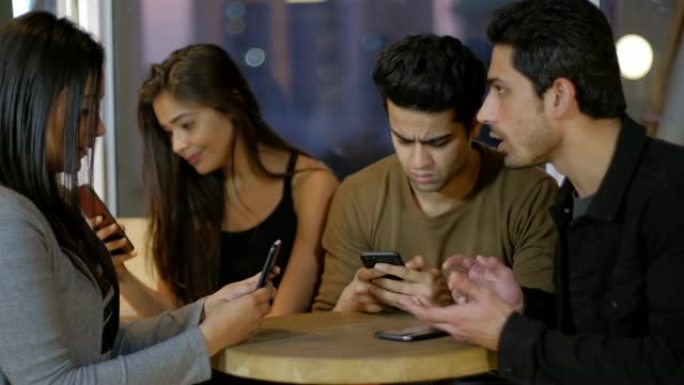 年轻的朋友忙于沉迷于各自的手机，直视着手机，不为所动，忽略了他们的朋友如何试图引起他们的注意，但惨败