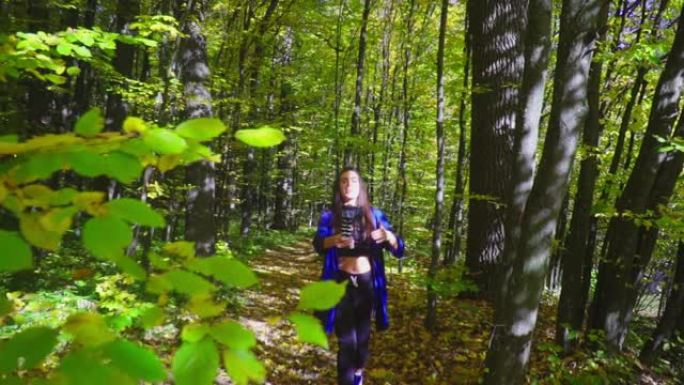 黑发年轻女性博客作者正在秋天的森林中行走，并使用相机录制vlog视频
