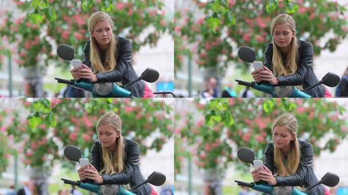 可爱的年轻女子骑着踏板车看着手机