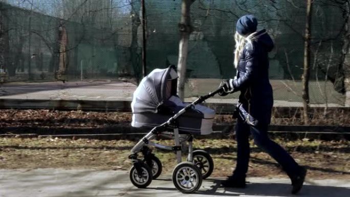 年轻的母亲带着婴儿车散步